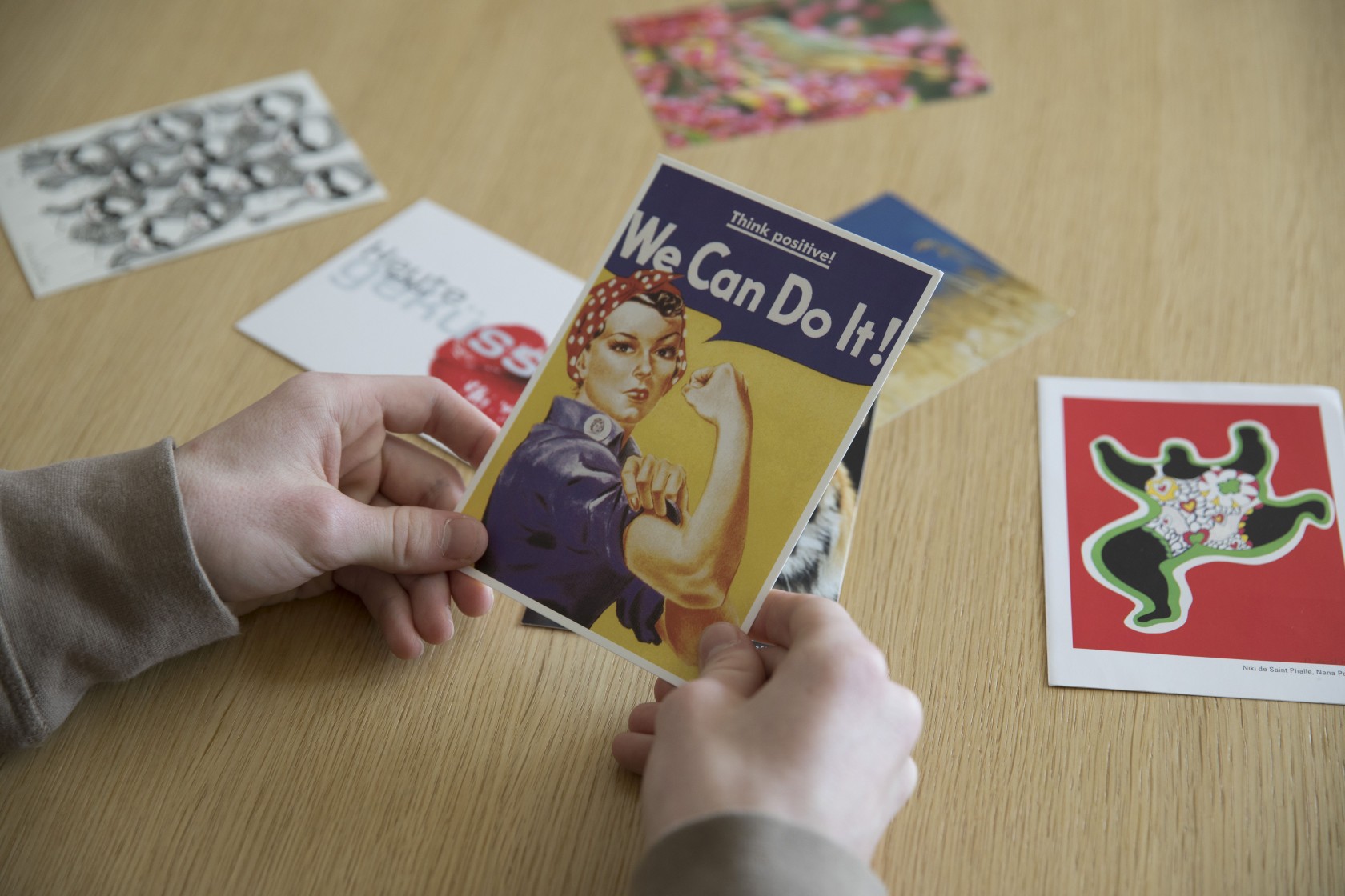 Zwei Hände halten eine Karte, auf dieser «We Can Do It!»