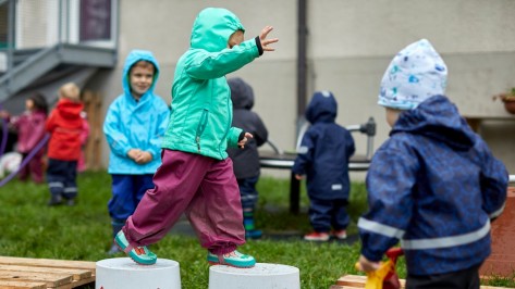 Kinder spielen im Garten. Ein Kind balanciert über Eimern.